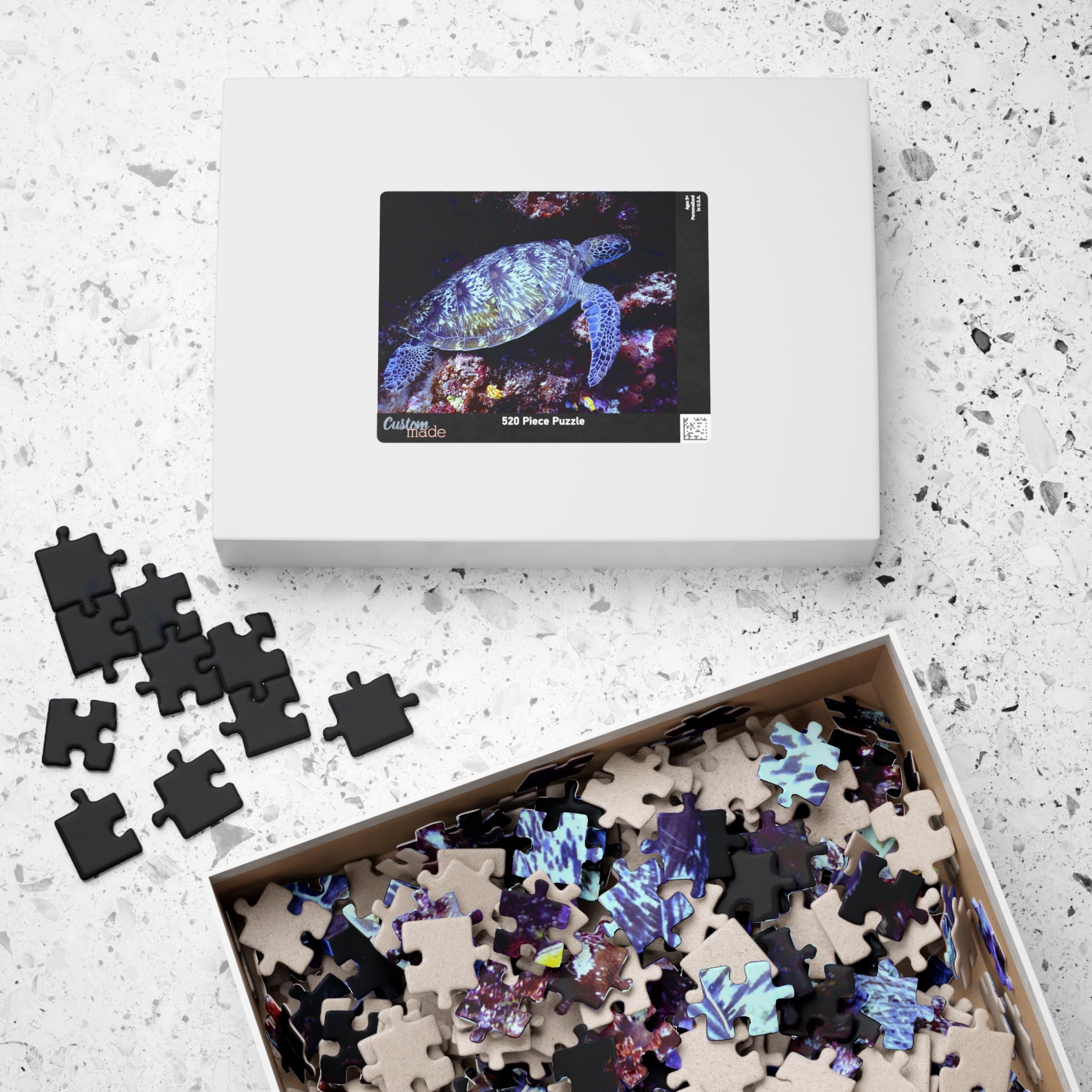 Puzzle tortue marine : boîte blanche et pièces noires et colorées dans un coffret