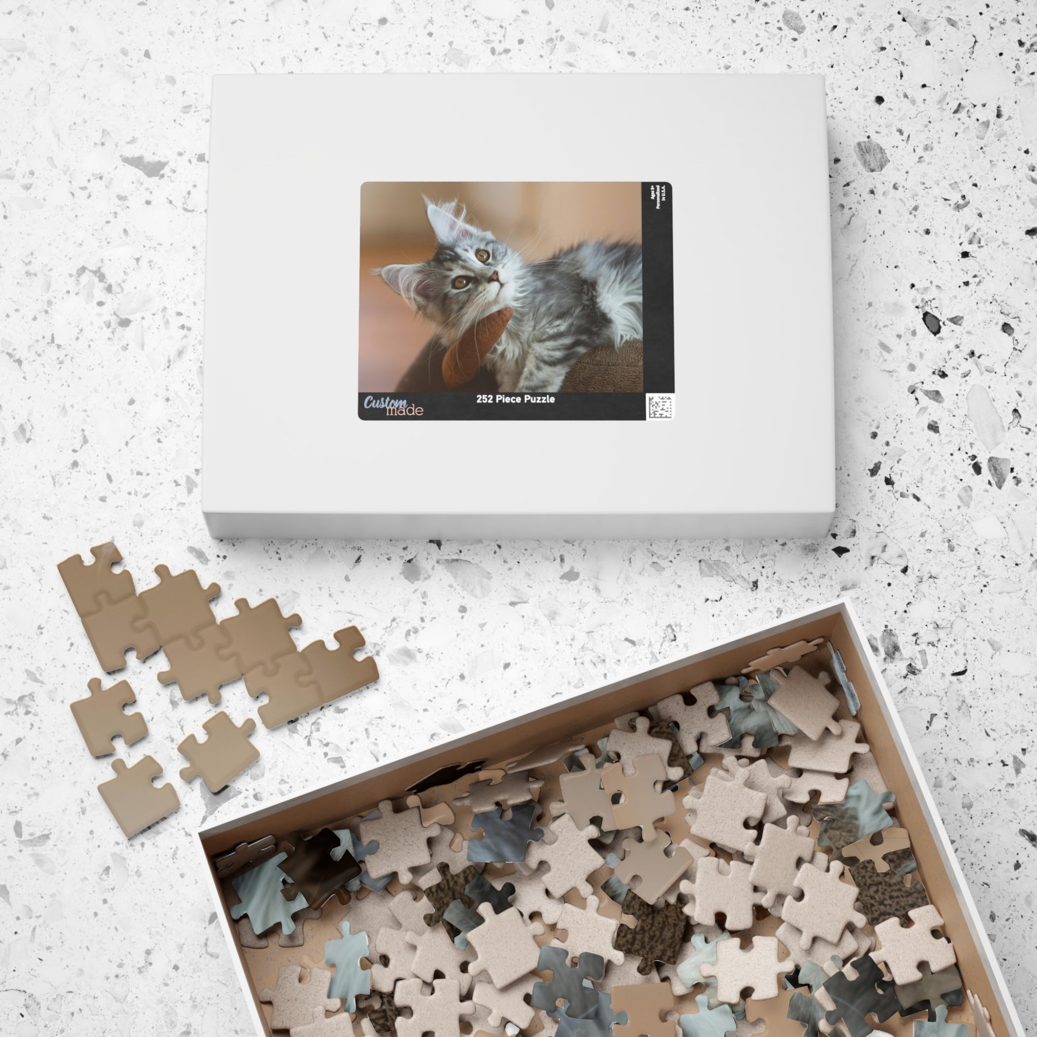Boîte de puzzle et pièces en carton beige, visuel de chat gris sur l’emballage