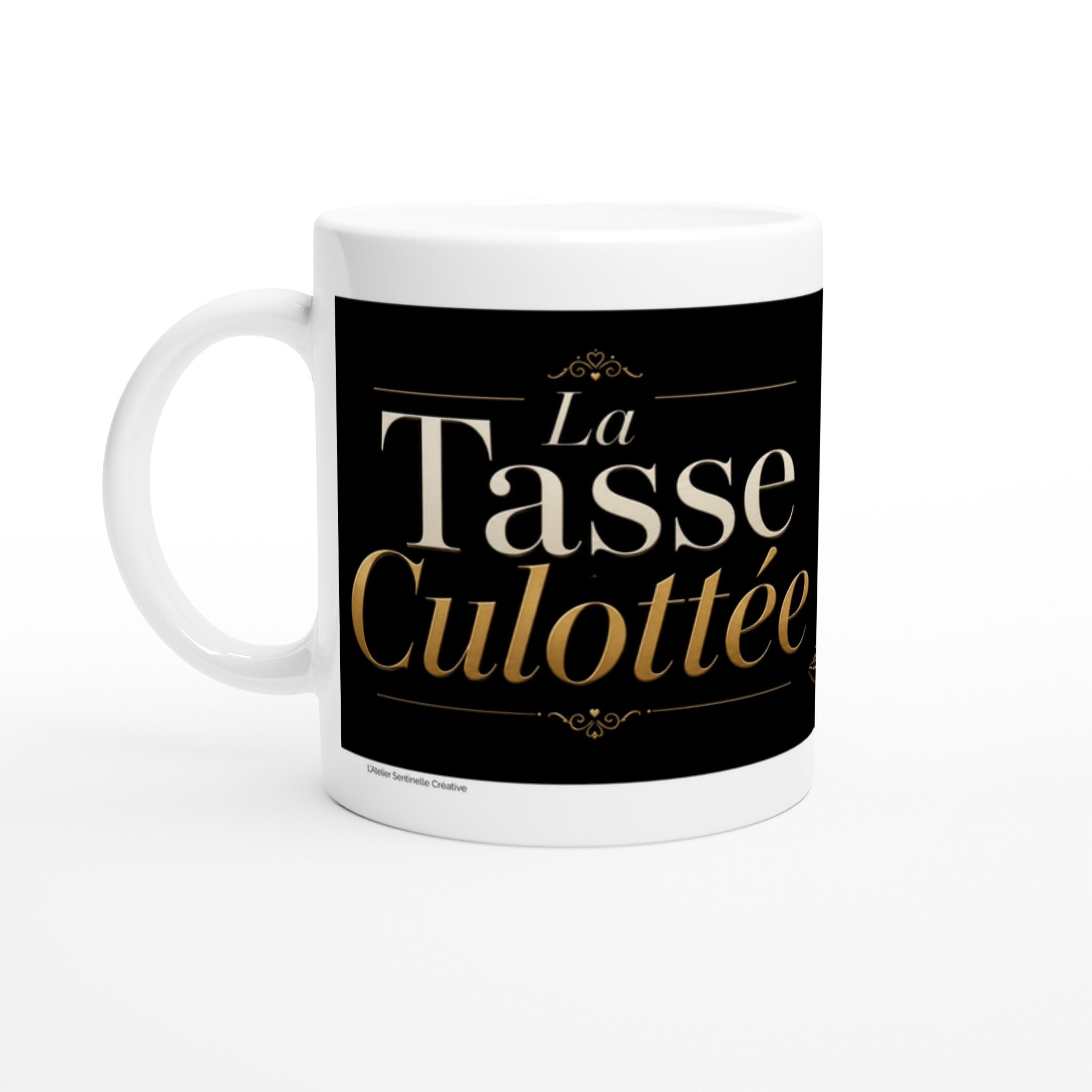 Tasse blanche avec lettrage doré « La Tasse Culottée » sur fond noir.