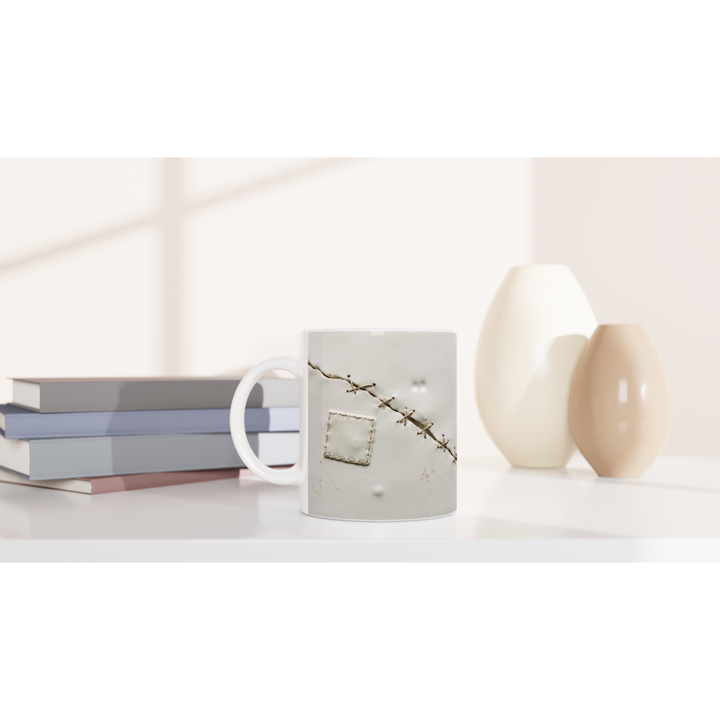 Mug en céramique blanche avec sutures décoratives et petit pansement en forme de rectangle.