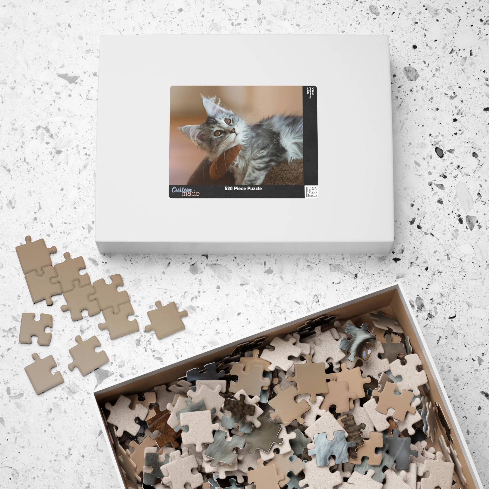 Puzzle en boîte avec chat gris, pièces au fond du coffret