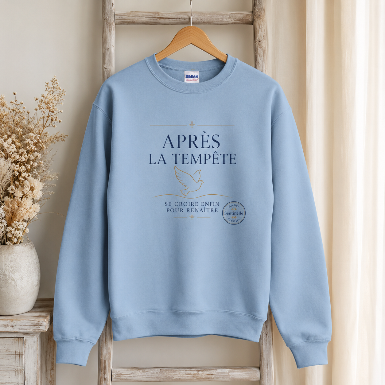 Sweat-shirt unisexe bleu clair sur cintre, impression « Après la tempête » sur l’avant