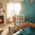 Tasse blanche avec texte « Pas une héroïne, Juste là », tenue à la main.