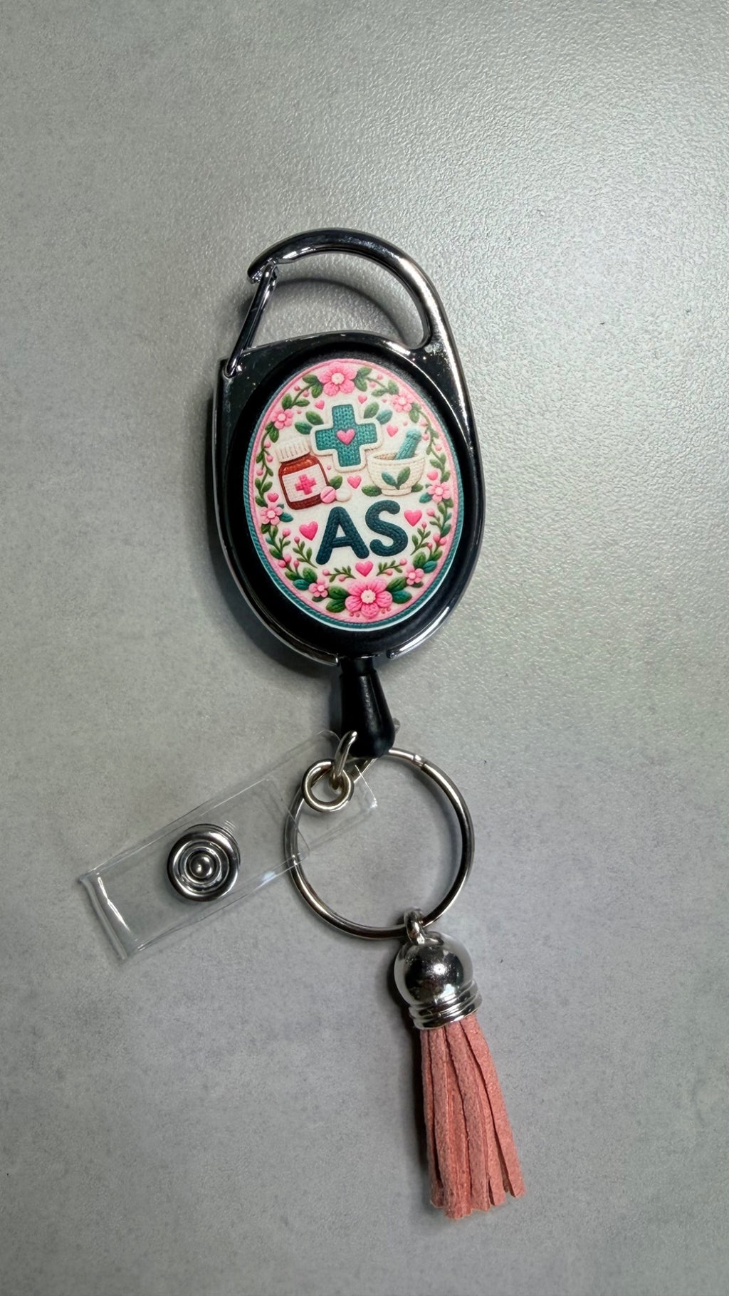 Porte-badge noir avec badge AS et fleurs, mousqueton métal, pompon corail