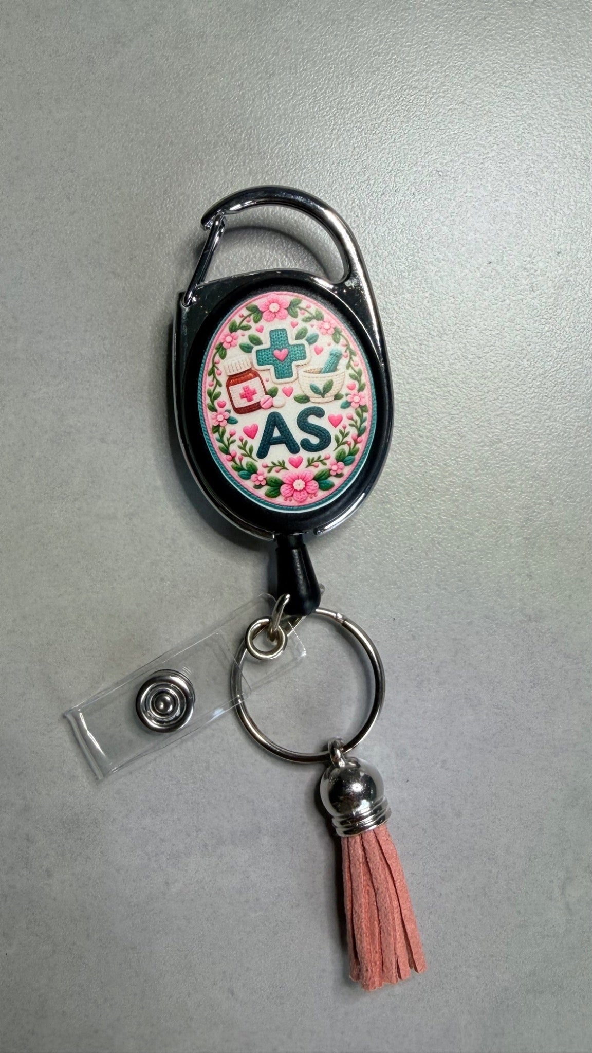 Porte-badge noir avec badge AS et fleurs, mousqueton métal, pompon corail
