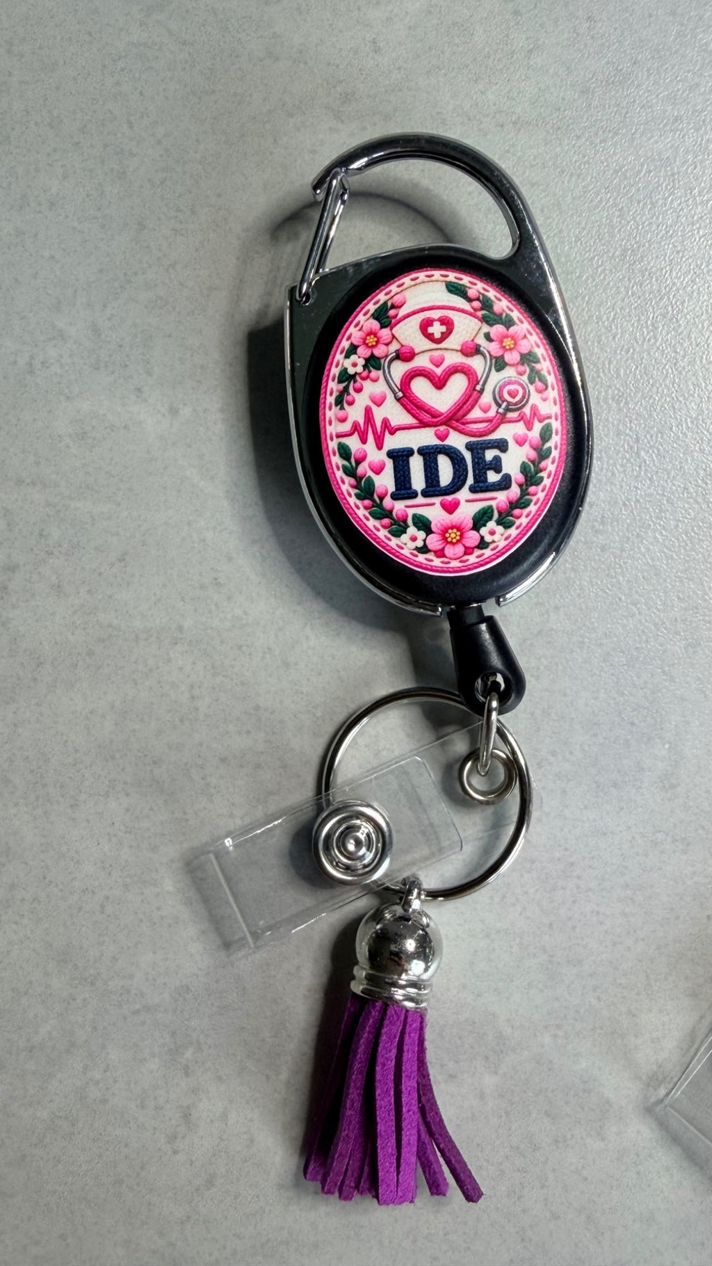 Porte-badge noir avec badge IDE rose, anneau métal et pompon violet