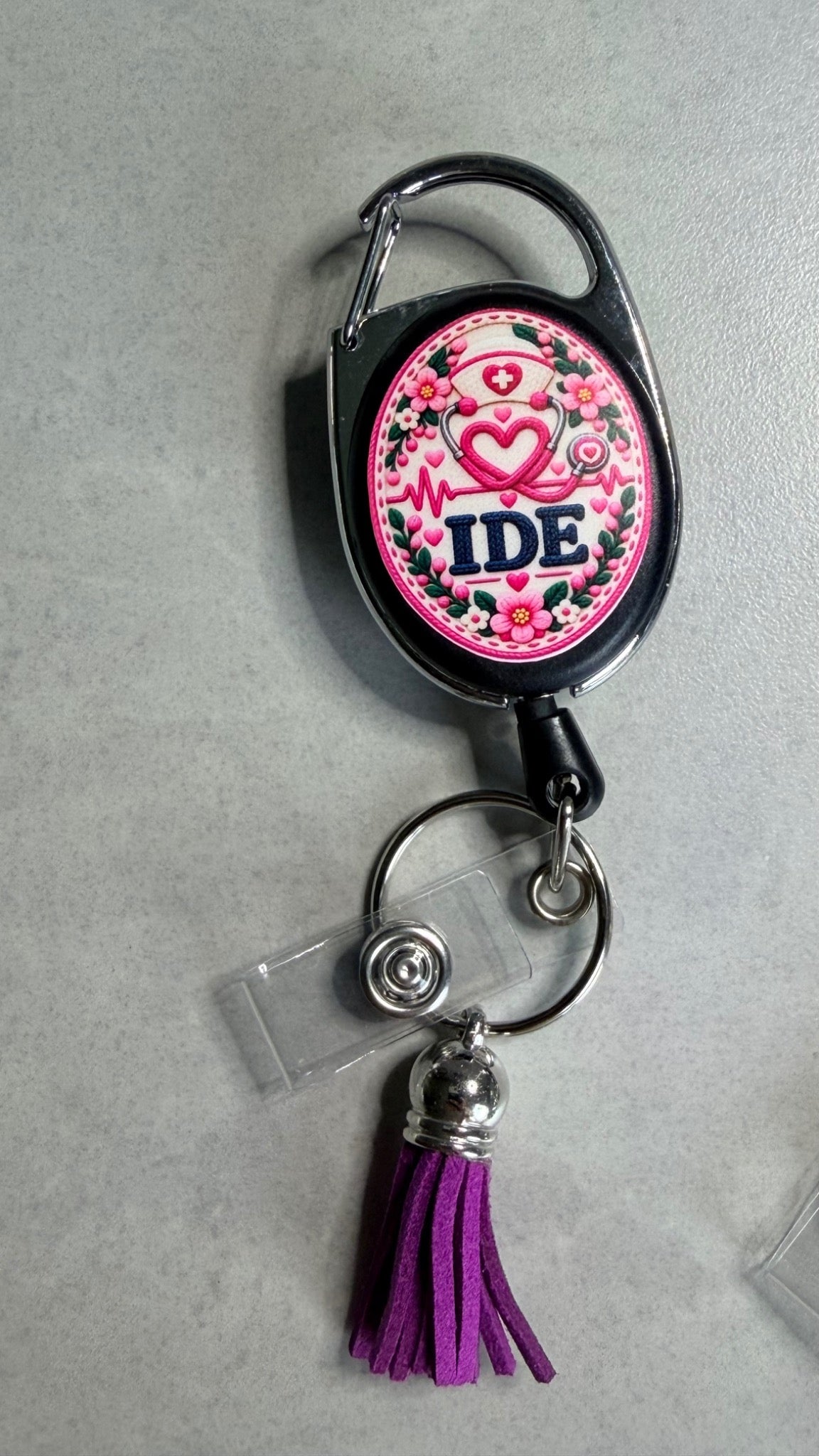 Porte-badge noir avec badge IDE rose, anneau métal et pompon violet