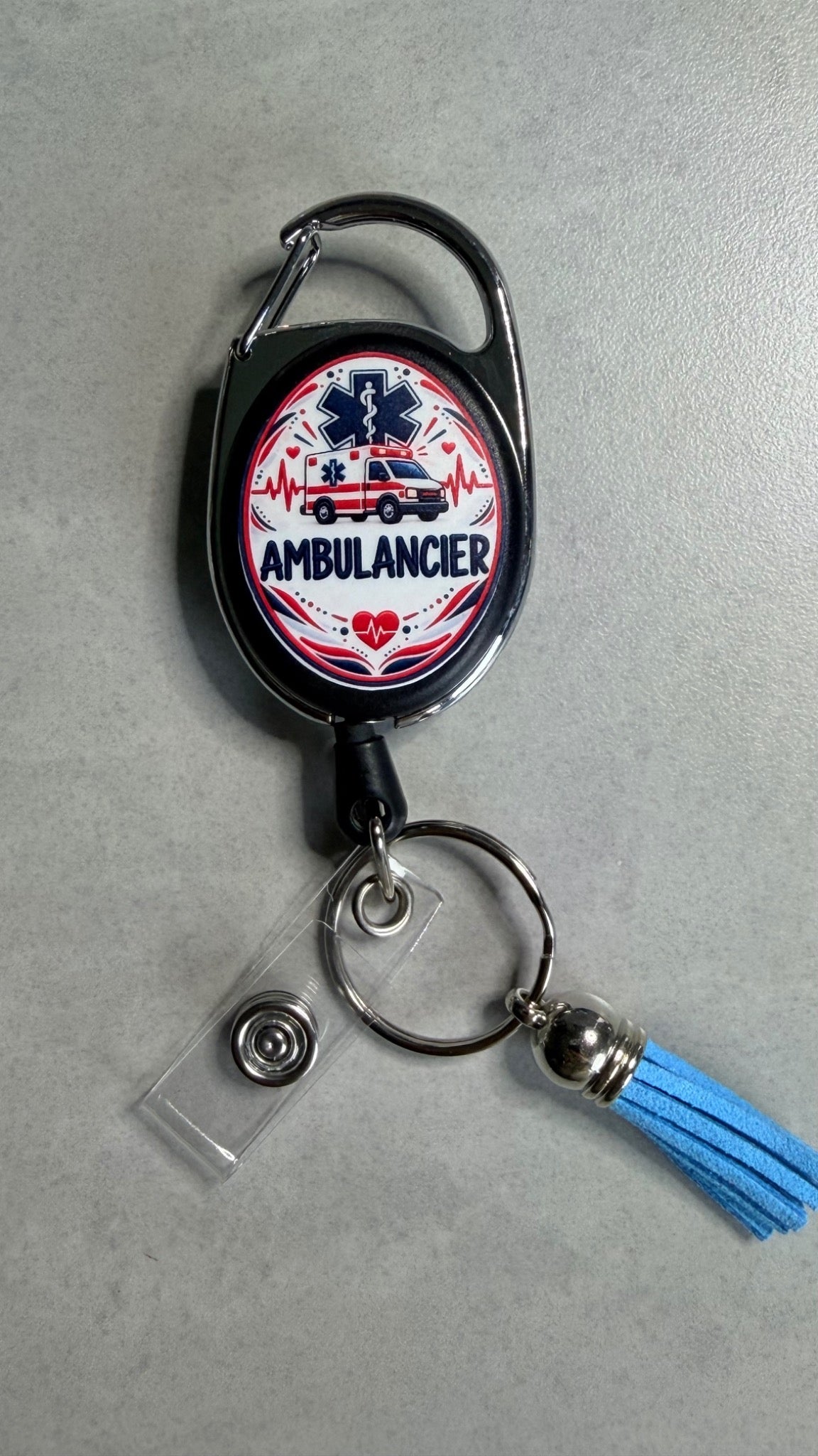 Porte-badge noir avec badge Ambulancier, tour de cou métal et pompon bleu