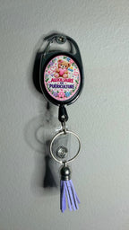 Porte-badge noir avec badge Auxiliaire puériculture, anneau métal et pompon violet