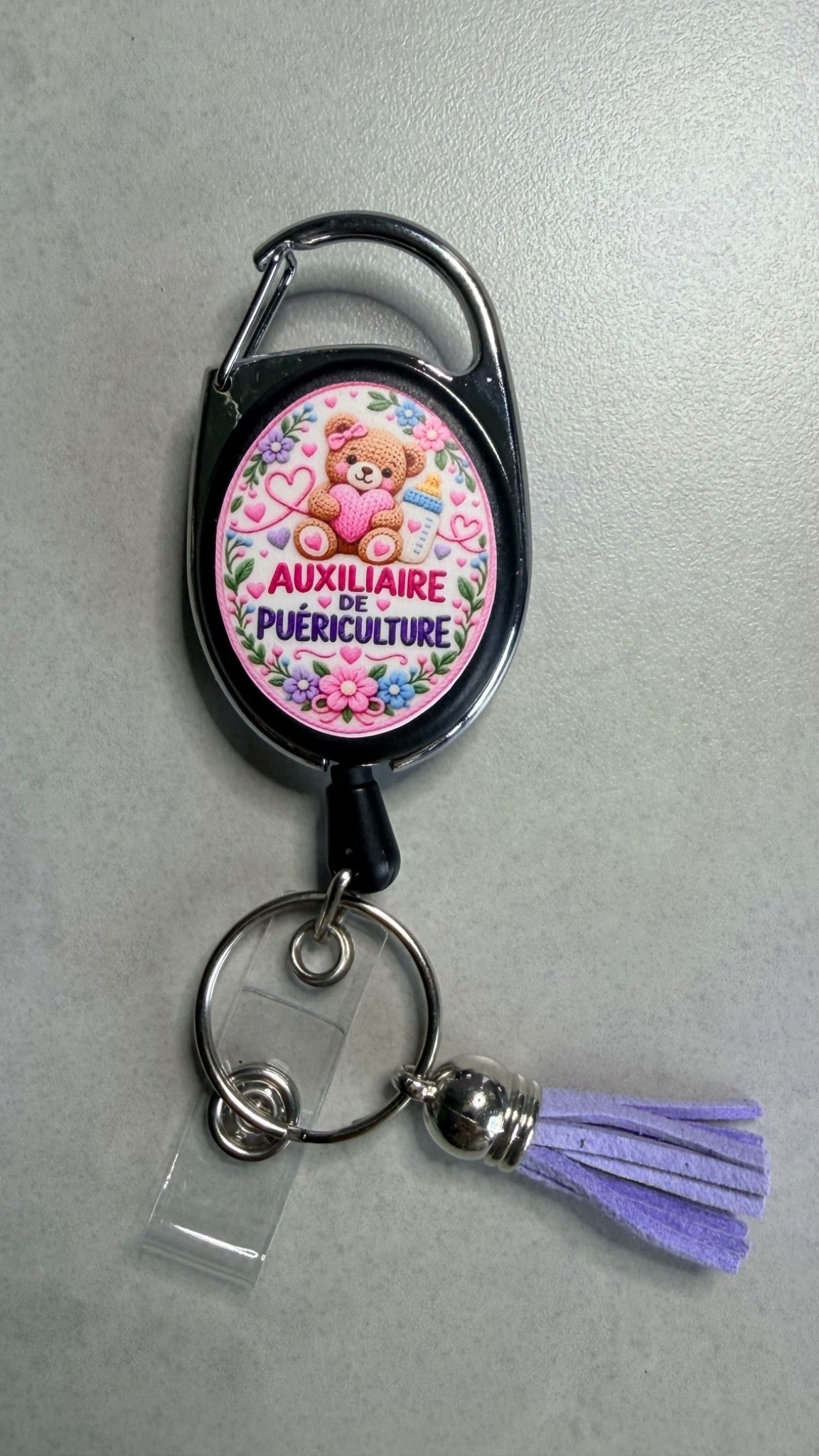Porte-badge noir avec badge Auxiliaire puériculture, mousqueton métal et pompon violet