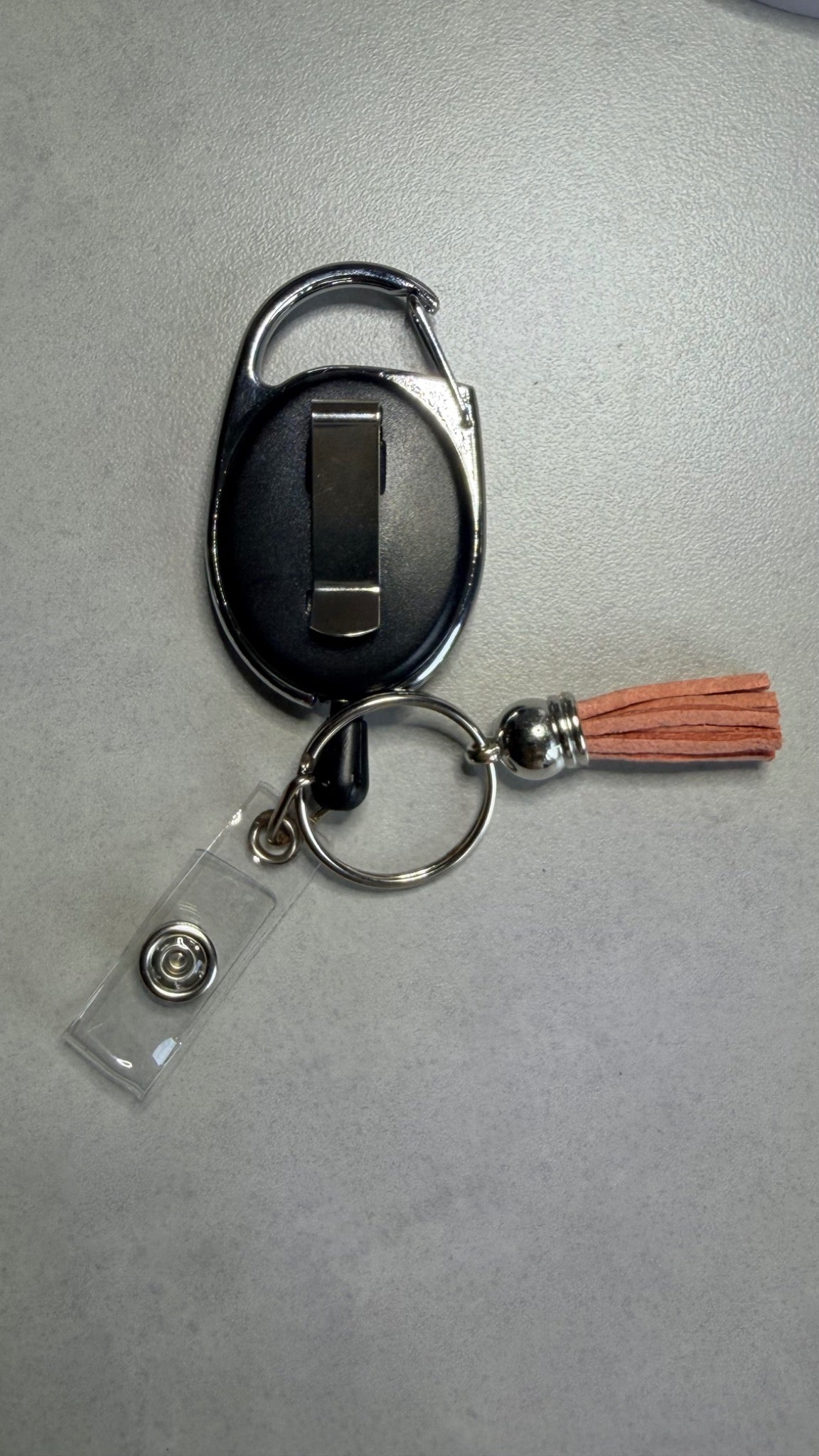 Porte-badge noir avec porte-médaillon ouvert, anneau métal et pompon marron