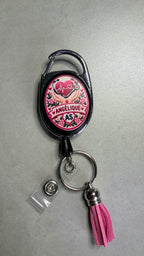 Porte-badge noir avec badge cœur rose, attache métal et pompon rose