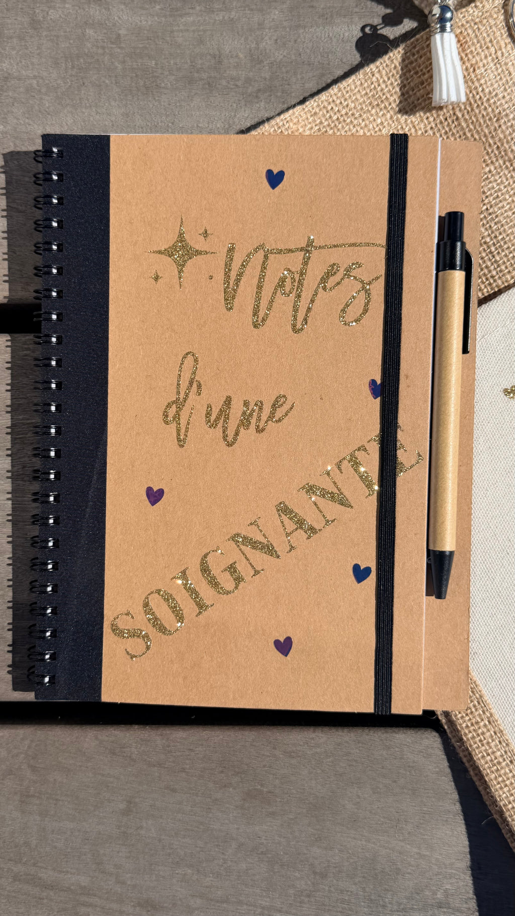 Carnet à spirale kraft avec inscription « soignante », stylo et reliure noire.