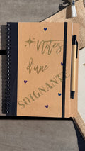 Carnet à spirale kraft avec inscription « soignante », stylo et reliure noire.